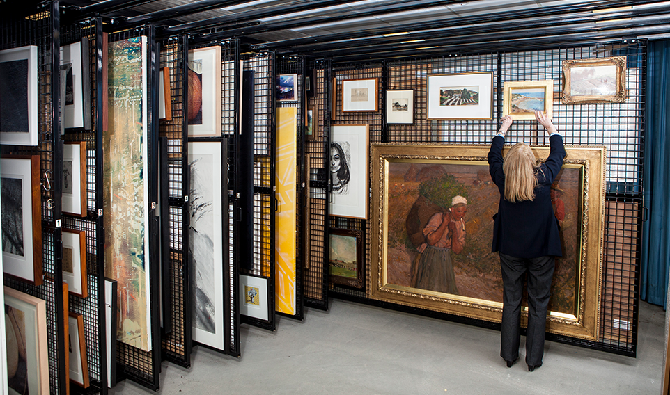 Room filled with sliding wire racks, each rack filled with multiple art pieces