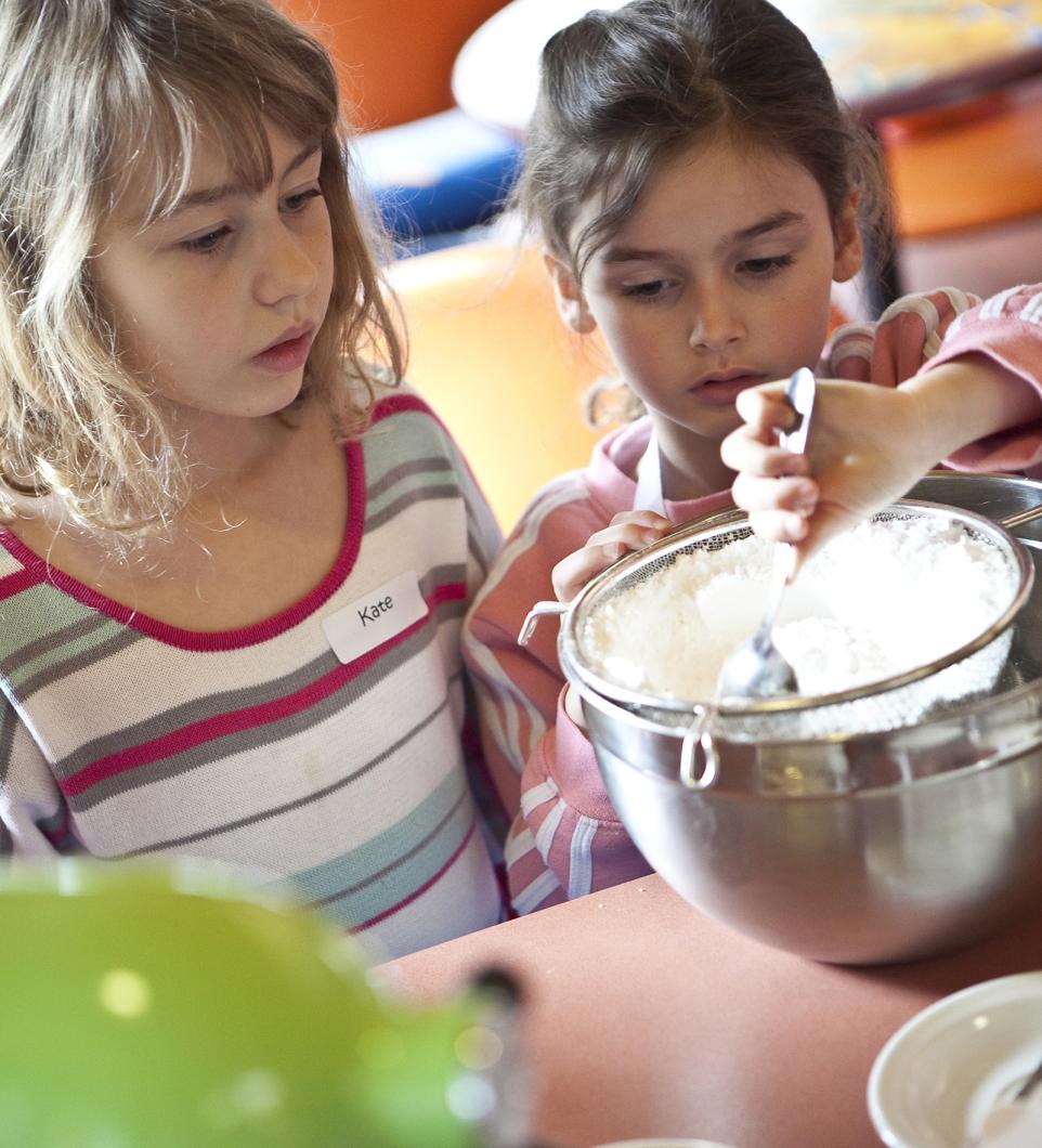 children stirring mixture in bowl during cooking class 