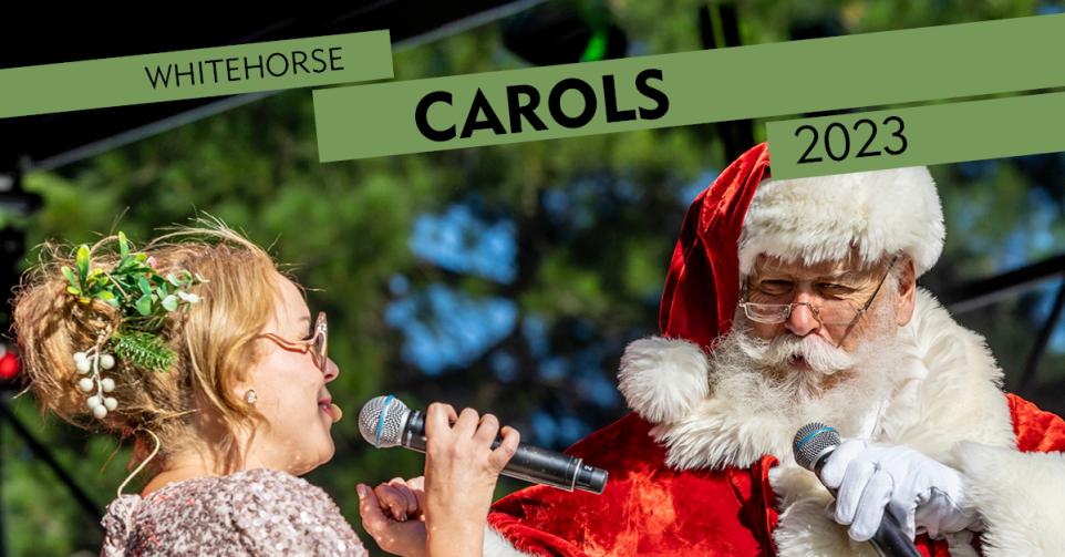 Santa singing into a microphone to a blonde women to his left