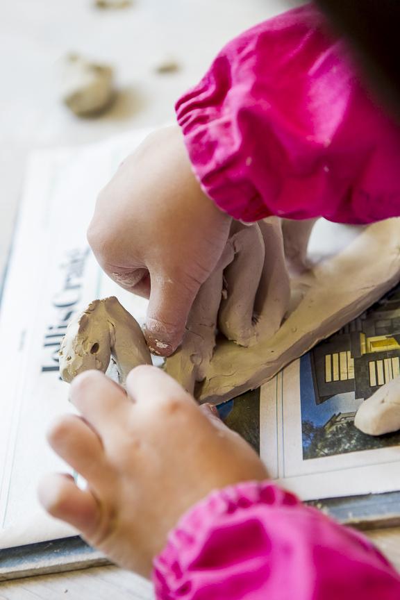 child hand building with clay