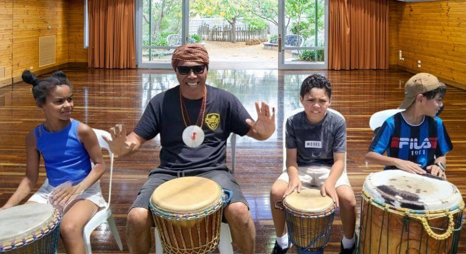 children and instructor Jose Mesquita in a drumming workshop
