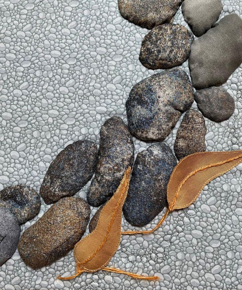 Detail of textile art depicting stone paving and leaves