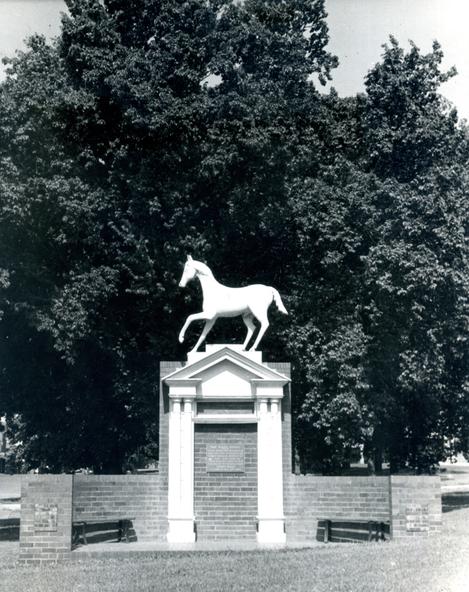 Black and white photograph of a white horse statue in a park