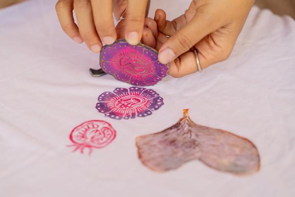 Three printed images made by a small printing plate held by a pair of hands