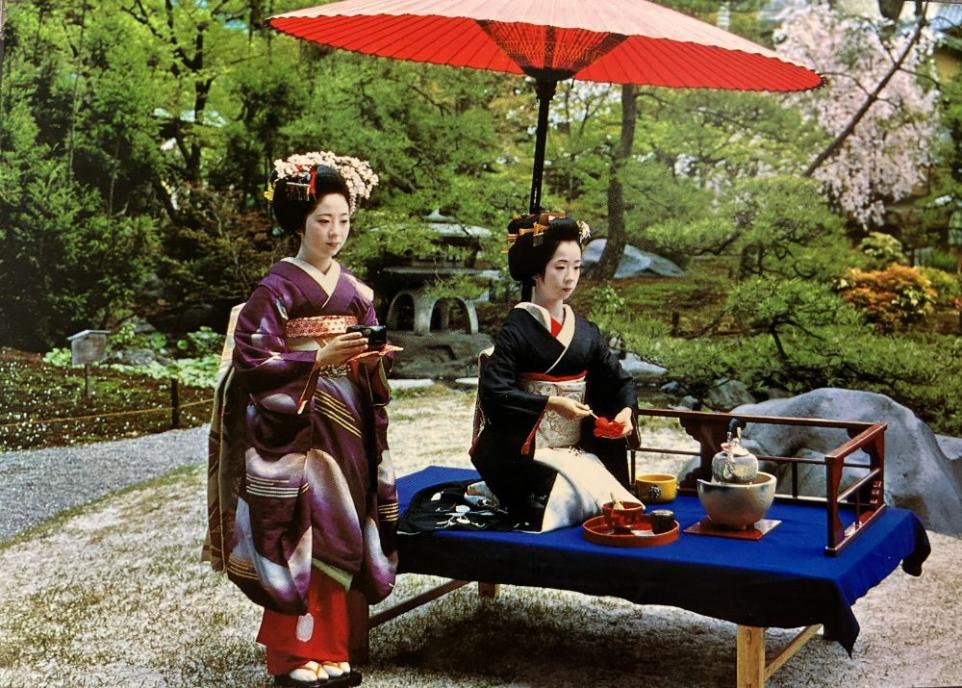 Staged image showing two geishas performing a tea ceremony in a garden