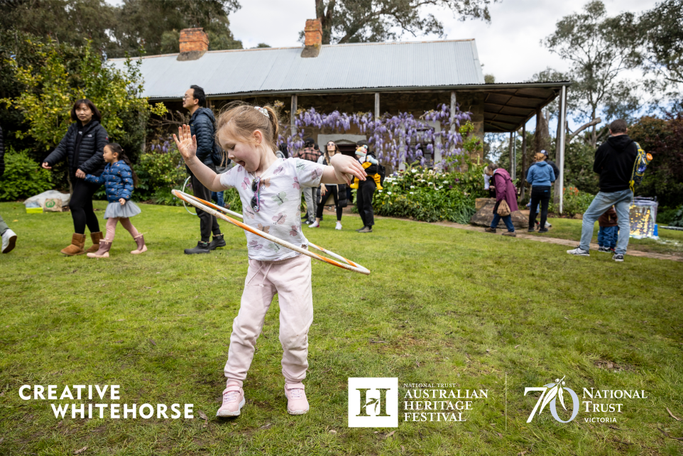 A photograph of a young girl playing with a hula hoop outside Schwerkolt Cottage