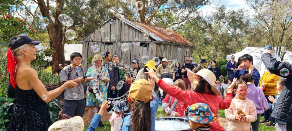 A crowd of people enjoying bubbles in a cottage garden.