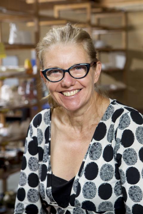 A lady with blonde hair and black framed glasses smiling at the camera