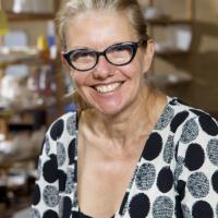 A lady with blonde hair and black framed glasses smiling at the camera