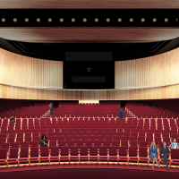 Large theatre space with red chairs and light wooden walls