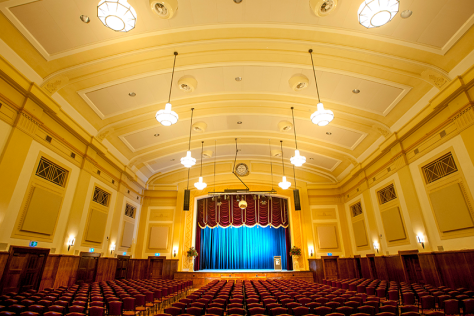 The Box Hill Town Hall's main hall set up with chairs and a blue lit stage