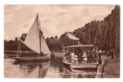 Sepia postcard depicting a boat and steam ferry on a lake.