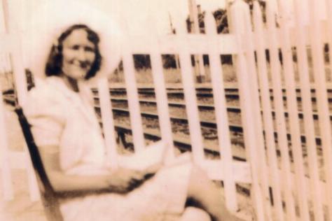 Woman seated by the rail station gates.