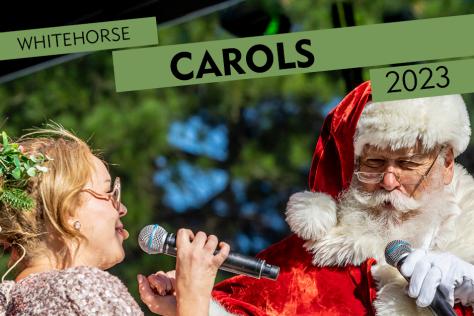 Santa singing into a microphone to a blonde women to his left