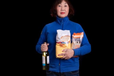 Portrait of a Chinese lady holding a bottle of wine and bag of instant oats