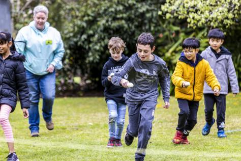 Children running in a race with an egg and spoon.