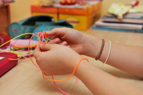 child's hands weaving wool together 