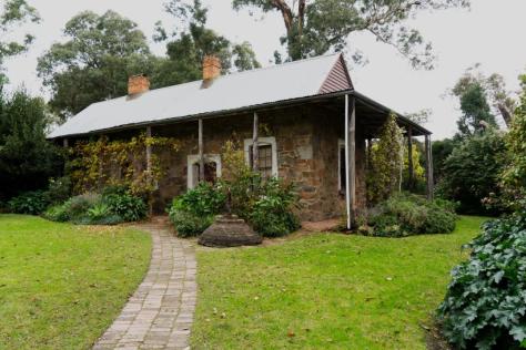 View of a pioneer stone cottage in a garden.