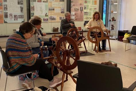 Group sitting together using spinning wheels.
