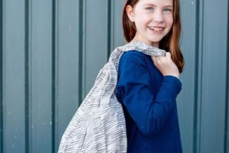 Young child holding  a bag over shoulder 