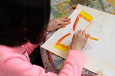 young child drawing a butterfly with pastels 