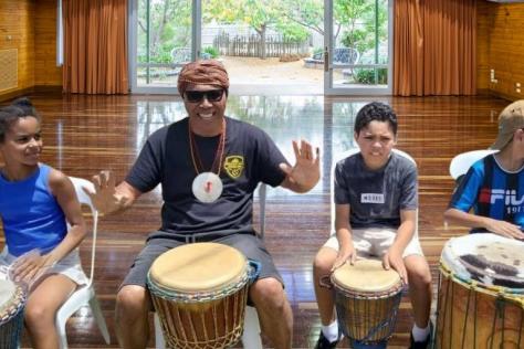children and instructor Jose Mesquita in a drumming workshop