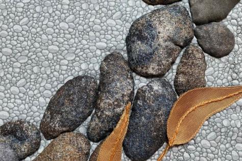Detail of textile art depicting stone paving and leaves