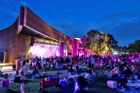 Photograph of The Round at twilight with a crowd gathered watching a stage performance outdoors.