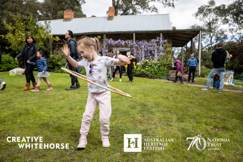 A photograph of a young girl playing with a hula hoop outside Schwerkolt Cottage