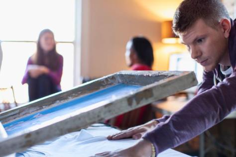 Young person screen printing on white shirt 