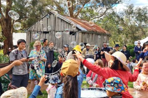 A crowd of people enjoying bubbles in a cottage garden.