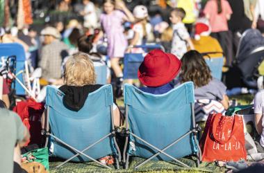 Two ladies sitting in low chairs watching a concert