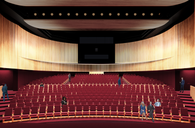 Large theatre space with red chairs and light wooden walls
