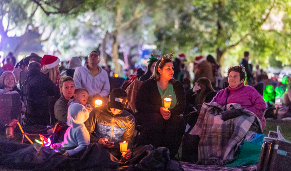 A family watching a Carols performance in the dark with their candles 